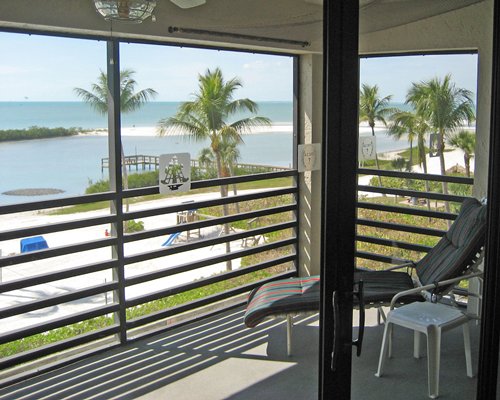 A balcony with chaise lounge chair facing the beach.