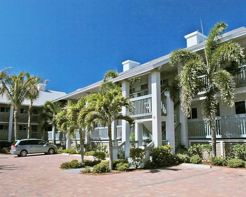 Exterior view of multiple unit balconies with parking lot and palm trees.