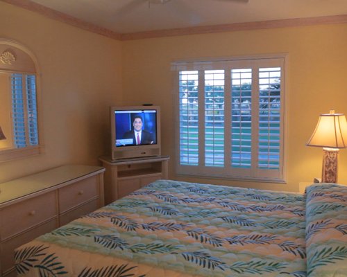 A well furnished bedroom with king bed and a television.