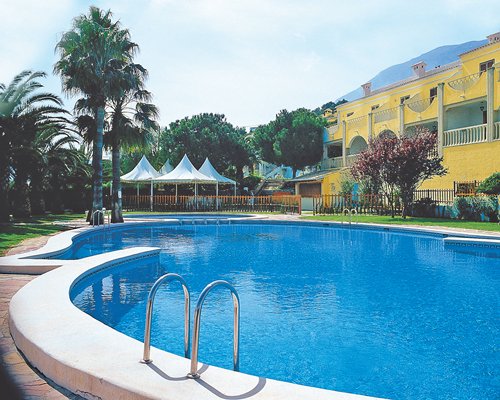 An outdoor swimming pool with palm trees alongside the resort.