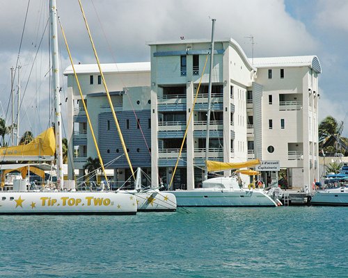 Exterior view of multiple unit balconies at Green Blue Houses alongside ocean with boats.