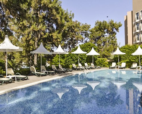 Scenic outdoor swimming pool with chaise lounge chairs and sunshades.