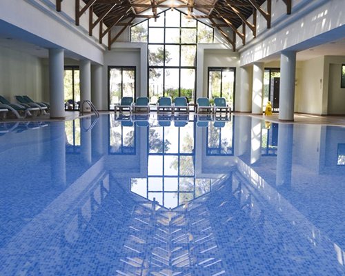 An indoor swimming pool with chaise lounge chairs.