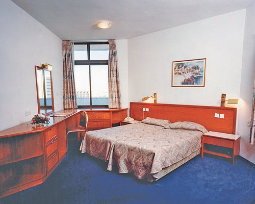 A well furnished bedroom with twin beds television and outside view.