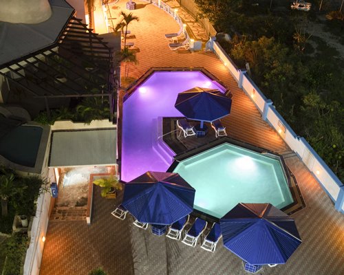 View of multiple unit balconies with outdoor swimming pool sunshade and chaise lounge chairs.