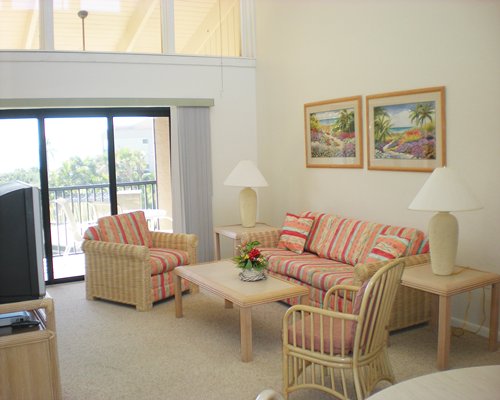 A well furnished living room with television dining area and balcony.