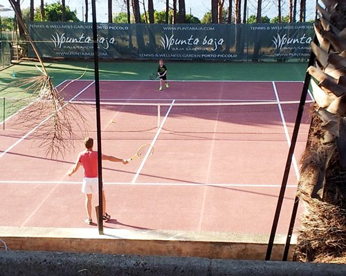 Outdoor recreation area with a view of people playing tennis at the tennis court.