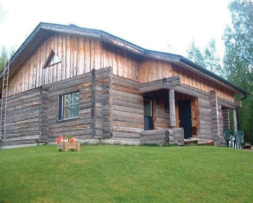 A wood paneled resort villa alongside a manicured lawn.