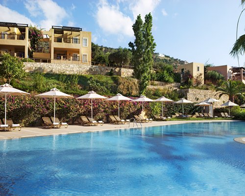 An outdoor swimming pool with chaise lounge chairs alongside resort condos.