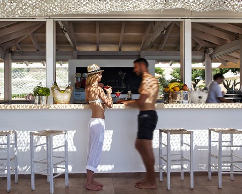Two people drinking cocktails in an outdoor bar.