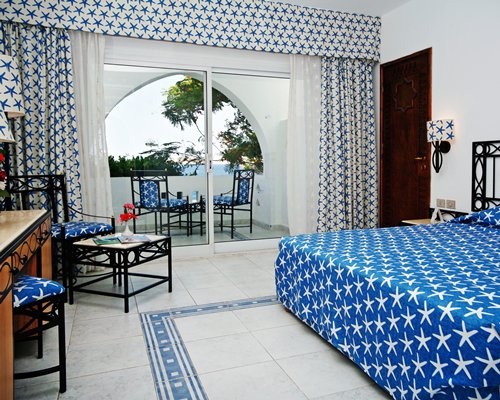 A well furnished bedroom with balcony and patio chairs.