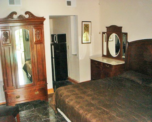 A well furnished bedroom with a queen bed and kitchen.
