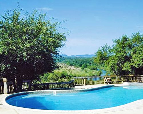An outdoor swimming pool surrounded by wooded area.