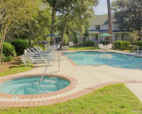 An outdoor swimming pool with hot tub alongside chaise lounge chairs.