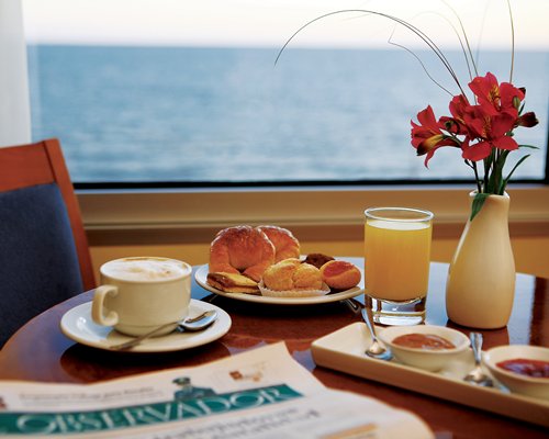 Various foods on a dining table with an ocean view.