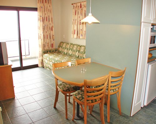 An open plan living room with a television dining table and an outside view.