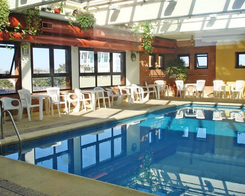 An indoor swimming pool with patio furniture and an outside view.