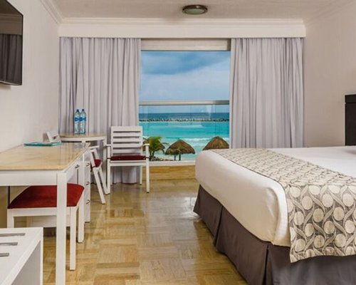 A bedroom with king bed and television alongside an outdoor view.