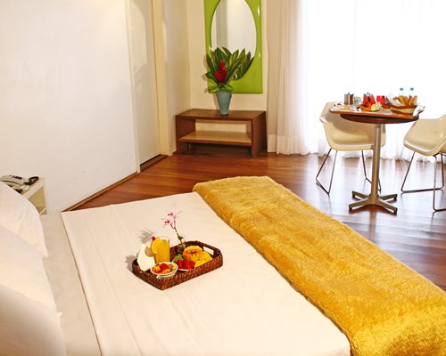 A well furnished bedroom with dining area outside view and food on the bed.