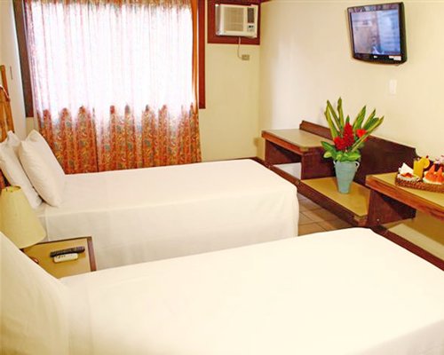 A well furnished bedroom with two beds and a television.