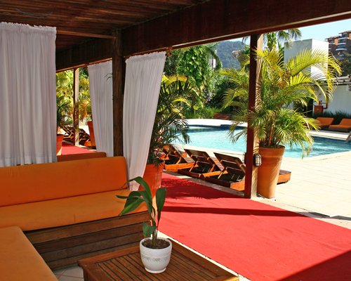 An outdoor lounge area alongside swimming pool with chaise lounge chairs.