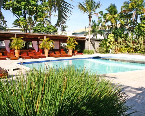 An outdoor swimming pool with chaise lounge chairs alongside landscaping.