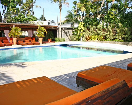 An outdoor swimming pool with chaise lounge chairs alongside landscaping.