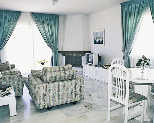 An open plan living and dining area with a pull out sofa and a television.