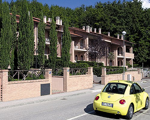 A street view of the Carpediem Assisi Living Club alongside a Volkswagen Beetle.