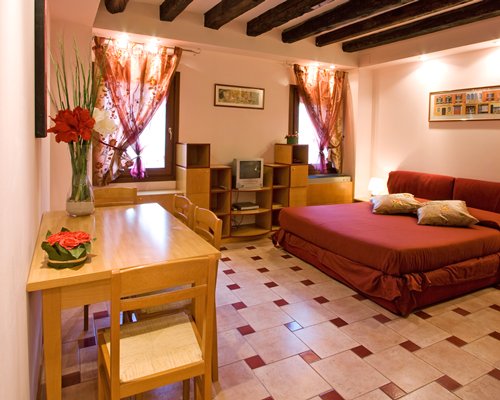 A well furnished bedroom with a television and wooden dining table.
