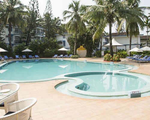 Outdoor swimming pool with chaise lounge chairs sunshades and patio furniture.