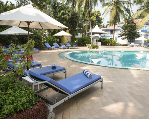 An outdoor swimming pool with chaise lounge chairs and sunshades.