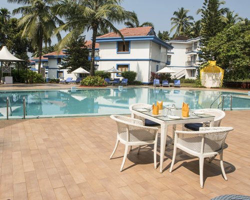 An outdoor swimming pool with chaise lounge chairs sunshades and patio furniture.