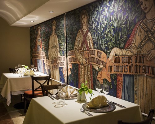 A restaurant interior with multiple dining tables and wall mural.