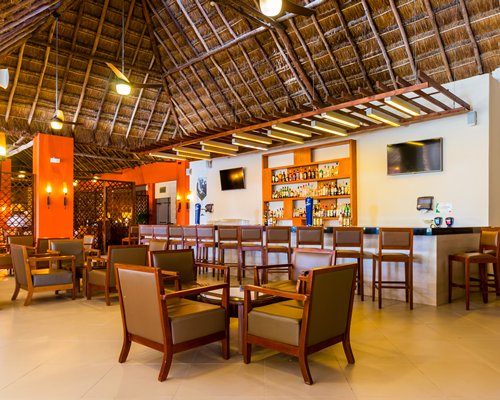 A resort bar and lounge area with tables and high thatched ceiling.