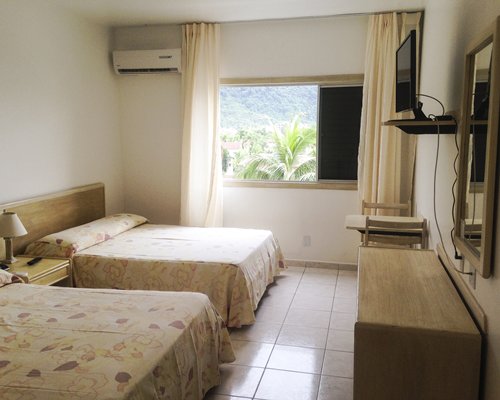 A well furnished bedroom with two beds television and an outside view.