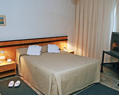 A well furnished bedroom with double bed and television.