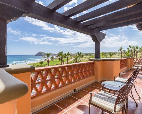 A balcony view of the beach with patio furniture.