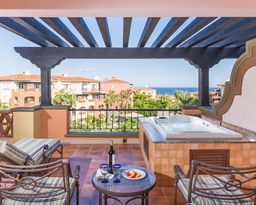 A balcony with chaise lounge chairs hot tub and an outside view.