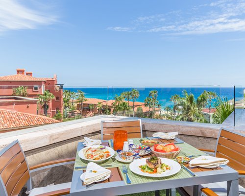 A balcony with various food items on a patio alongside the beach.