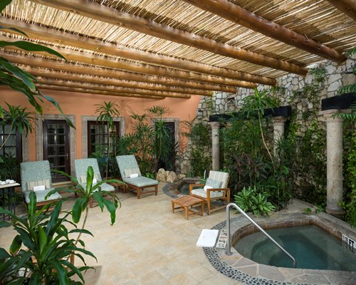 An indoor hot tub with chaise lounge chairs and landscaping.