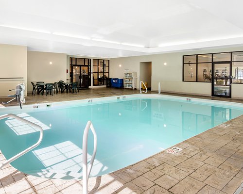 An indoor swimming pool with patio furniture.
