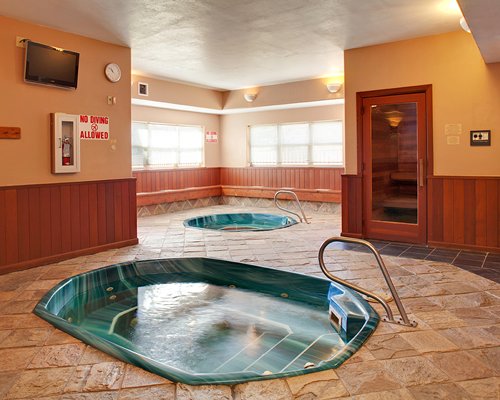 An indoor two hot tubs with an outside view.