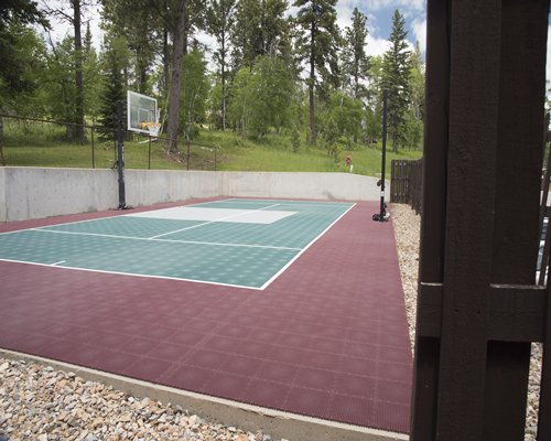 An outdoor basketball court surrounded by a wooded area.