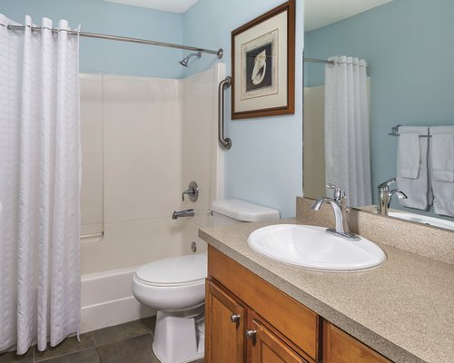 A bathroom with a toilet bathtub shower and single sink vanity.