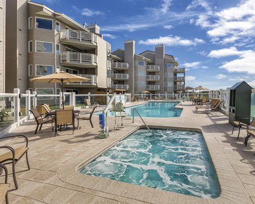An outdoor swimming pool with patio furniture alongside resort condos.