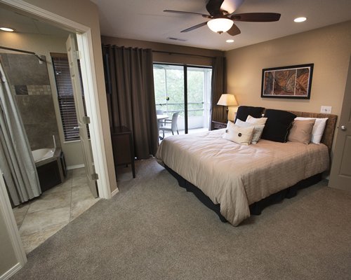 A well furnished bedroom with a balcony and bathroom.