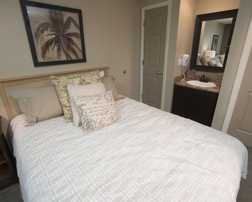 A well furnished bedroom with a queen bed and closed sink vanity.
