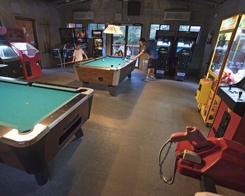 An indoor recreation room with arcade games and pool tables.
