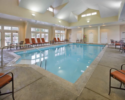 An indoor swimming pool with patio furniture.